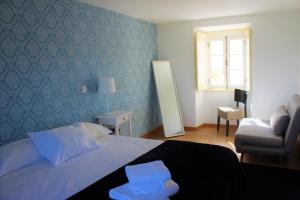 オウレーンにあるCasa do Castelo Ourémのベッドルーム1室(ベッド1台、椅子、窓付)