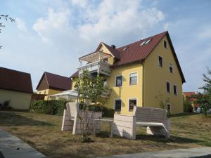 uma casa amarela com duas cadeiras à frente em Pension-Gästehaus Küblböck em Neualbenreuth