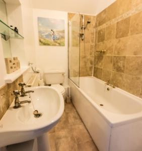 a bathroom with a sink and a tub and a toilet at Newlyn House - Sleeps 11 in Chester