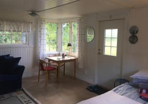 a bedroom with a desk and a table and windows at Lillstugan Elofstorp in Kristinehamn