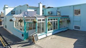 un edificio azul con un cartel delante en The Addresse on the Beach en Tramore