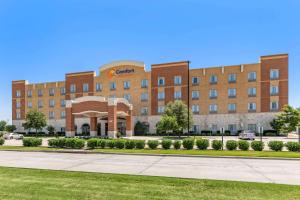 a large red brick building with a courtyard at Comfort Suites Frisco in Frisco