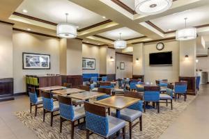 a dining room with tables and chairs and a flat screen tv at Comfort Suites Frisco in Frisco