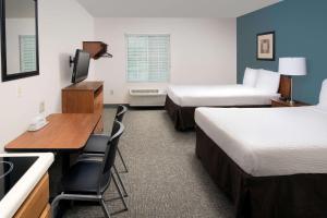 Habitación pequeña con 2 camas y escritorio. en WoodSpring Suites Gainesville I-75, en Gainesville
