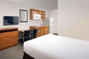 a hotel room with a bed and a desk and a kitchen at WoodSpring Suites Gainesville I-75 in Gainesville
