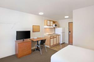 Pokój z biurkiem, telewizorem i łóżkiem w obiekcie WoodSpring Suites Jacksonville Beach Blvd w mieście Jacksonville