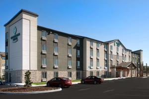 a large building with two cars parked in a parking lot at Woodspring Suites Orlando International Drive in Orlando