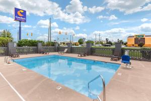 una piscina en un hotel con sillas y un cartel en Comfort Suites near Camp Lejeune, en Jacksonville