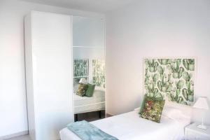 a white bedroom with a mirror and a bed at VV Canteras Oasis "by henrypole home" in Las Palmas de Gran Canaria