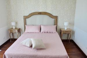 een slaapkamer met een groot bed met roze lakens en 2 tafels bij Casa Parthenope in Ercolano