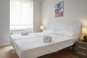 1 dormitorio con 2 camas blancas y ventana en Pausoka - Basque Stay en San Sebastián