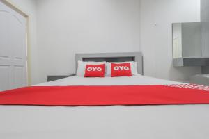 un letto bianco con due cuscini rossi sopra di OYO 1159 K&k Apartment a Samutprakarn