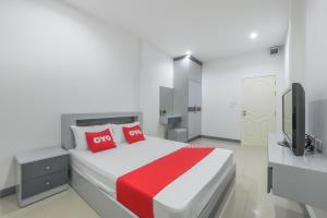 una camera da letto con un letto con cuscini rossi e una TV di OYO 1159 K&k Apartment a Samutprakarn