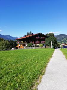 een groot gebouw met een grasveld naast een weg bij Gästehaus Midi in Reith im Alpbachtal