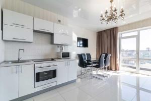 a kitchen with white cabinets and a table and chairs at Lux Most City Area, Panoramic city View in Dnipro