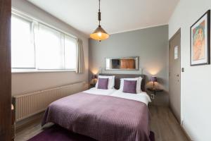 a bedroom with a large bed with purple blankets and pillows at Charmehotel Klokkenhof in Brasschaat