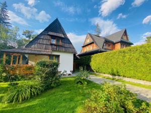 a house with a black roof and a green yard at Domek Leśny in Zakopane