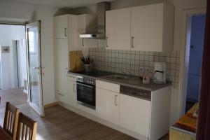 a kitchen with white cabinets and a sink at Ferienwohnung Jacobshof in Oberstedem