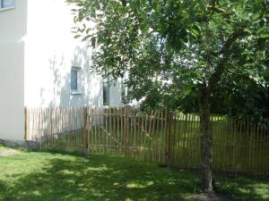a wooden fence with a tree in a yard at Ferienwohnung Jacobshof in Oberstedem