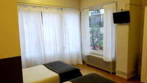 バルセロナにあるオスタル エル ニノートのベッドルーム1室(白いカーテン、ベッド1台、窓付)