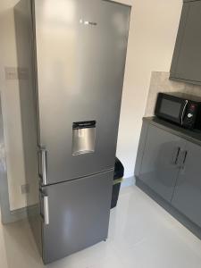 una nevera de acero inoxidable en una cocina con microondas en Dane Guest House Free Parking Fast WiFi Modern Living, en Burnley