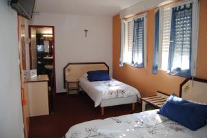 a small room with two beds and windows at Hôtel Myosotis in Lourdes