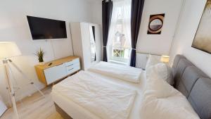 um pequeno quarto com uma cama e uma televisão em Lieblingsapartment mit 2 Schlafzimmern - Nördliche Altstadt in Rostock em Rostock