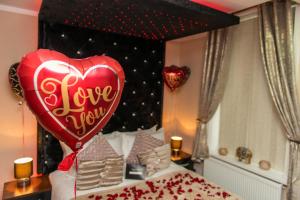 a heart balloon is on top of a bed at Aphrodite Suites in Bradford