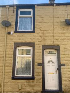ein Gebäude mit zwei Fenstern und einer weißen Tür in der Unterkunft Dane Guest House Free Parking Fast WiFi Modern Living in Burnley