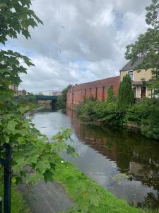 a river with a bridge in the background next to a building at Dane Guest House Free Parking Fast WiFi Modern Living in Burnley
