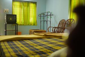 um quarto com uma cama e cadeiras e uma televisão em Jungleview Home Stay em Idukki