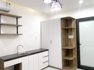 a kitchen with white cabinets and a sink and shelves at Bap Homestay in Hoi An