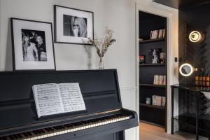 a black piano in a living room with pictures on the wall at Chouchou Hotel in Paris