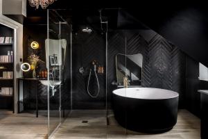 a black bathroom with a tub and a shower at Chouchou Hotel in Paris