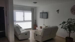 a living room with two chairs and a guitar at Casa Roca in Caleta De Fuste