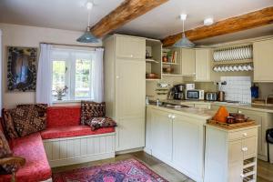 a kitchen with a red couch and a window at Tyas Cottage in Slaithwaite