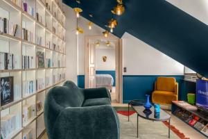 a living room with a couch and a chair and books at Chouchou Hotel in Paris