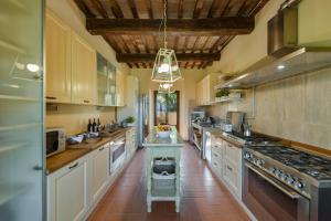 cocina grande con armarios blancos y suelo de baldosa roja en La Marrana - Castello del Terriccio, en Castellina Marittima