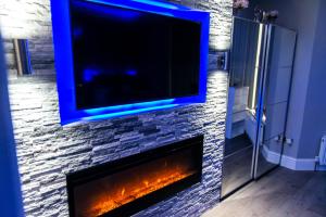 a living room with a fireplace with a tv above it at Velmora Suites Bradford in Bradford