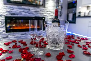 a bottle of wine and two glasses on a table with roses at Aphrodite Suites in Bradford