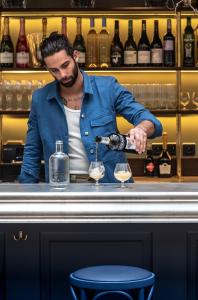 a man pouring wine into a glass at a bar at Chouchou Hotel in Paris