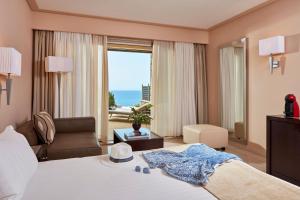 Atlantica Grand Mediterraneo Resort - Adults Only في Kompítsion: غرفة فندقية بسرير وإطلالة على المحيط