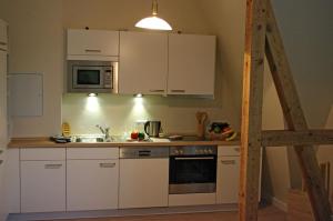 una cocina con armarios blancos y fregadero en Haus am See, en Berlín
