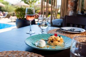 a table with a plate of food and a glass of wine at Parosland Hotel in Aliki