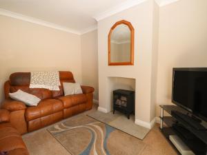 a living room with a brown leather couch and a fireplace at 1 Paythorne Farm Cottages in Henfield