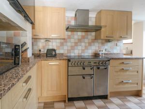 cocina con armarios de madera y estufa de acero inoxidable en 1 Paythorne Farm Cottages en Henfield