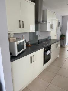 a kitchen with white cabinets and a microwave at Westerlies in Portrush