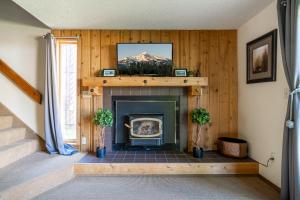a living room with a fireplace with a tv above it at Huckleberry House in West Yellowstone