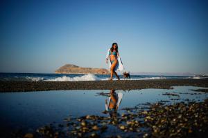 a woman walking on the beach with a surfboard at Alkionides Seaside Hotel in Platanias