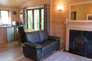 a living room with a leather couch and a fireplace at Cul Darach Lodge, Glen Roy Nature Reserve in Roybridge